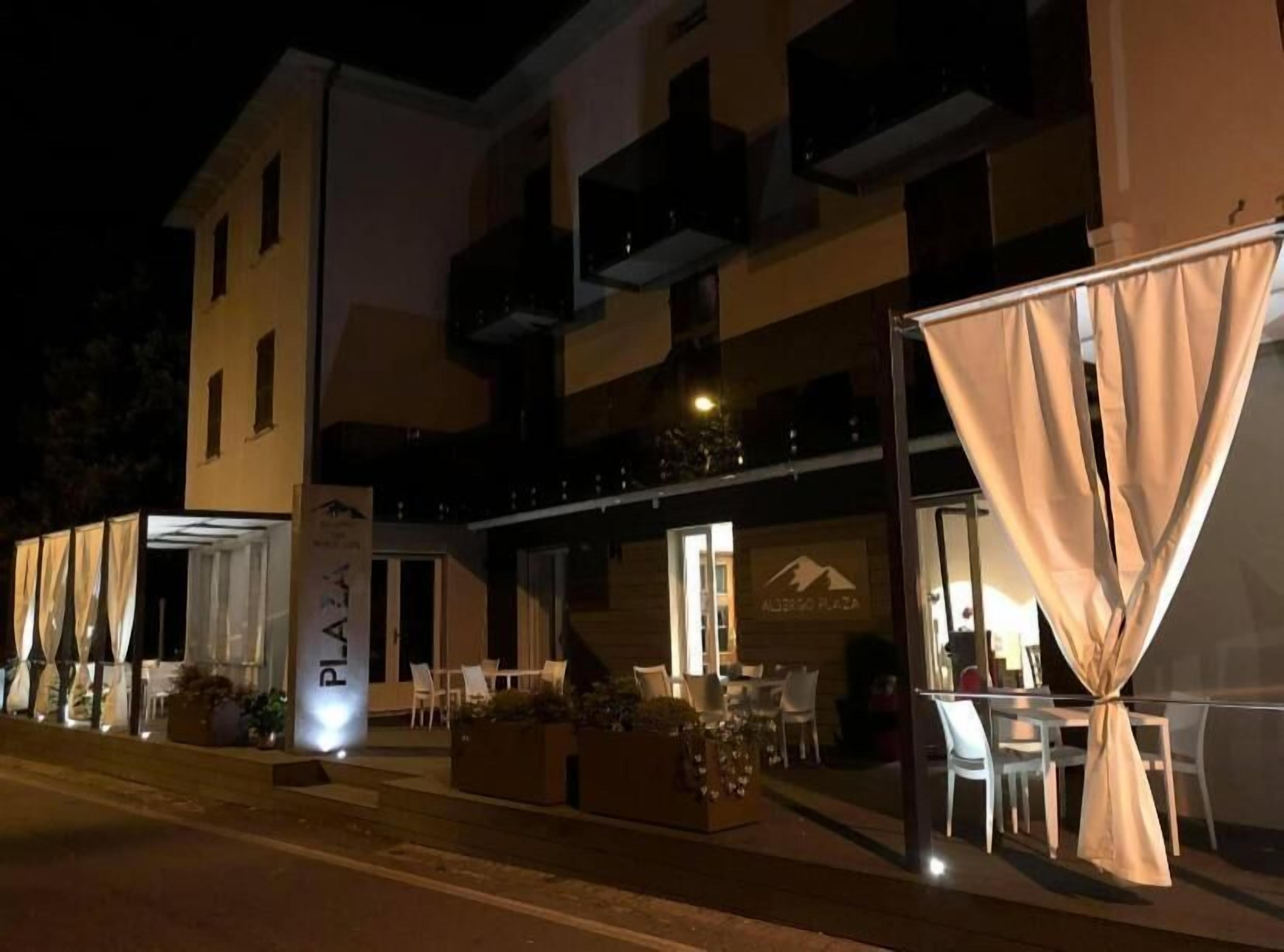 Un hotel con mesas al aire libre y un letrero que dice "PIALA".