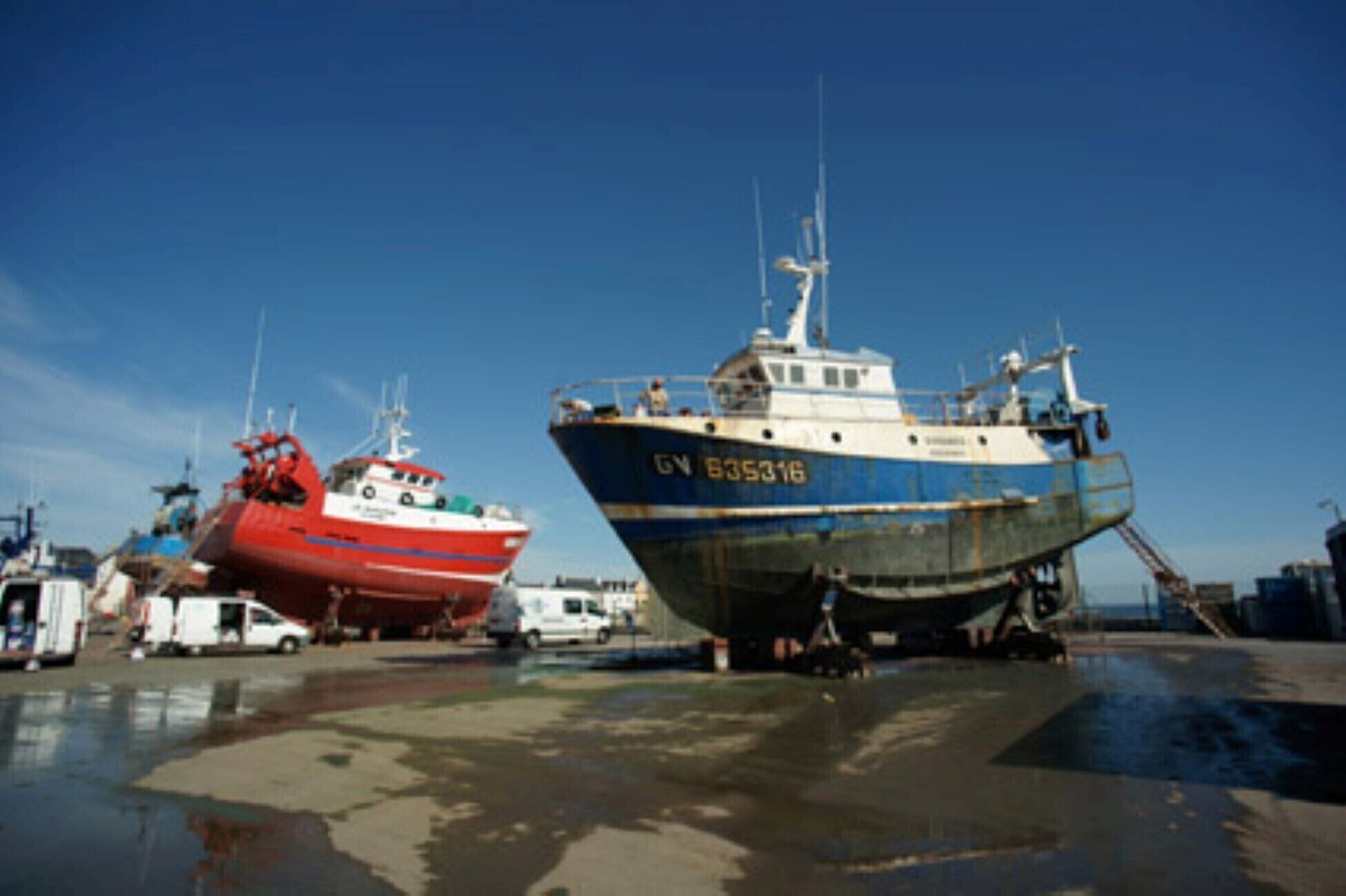 Dois barcos atracados em uma marina sob um céu claro.
