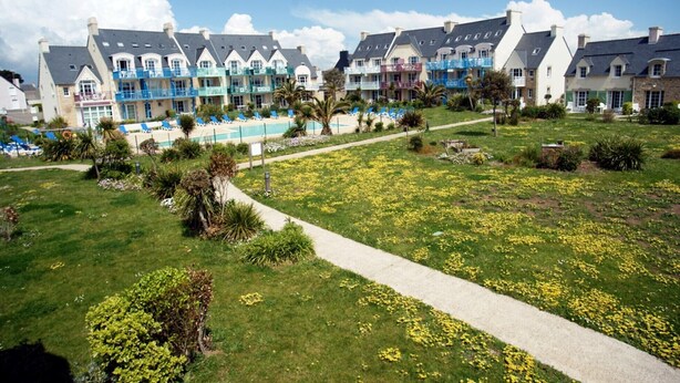 A hotel with a swimming pool, a garden with yellow flowers, and a pathway. - For rent 2 level house in seaside residence (Le Guilvinec)