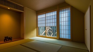 A traditional Japanese room with tatami flooring, sliding shoji doors, and a small wooden sculpture on the left. - Hotel ZIZI Kyoto Gion (Kyoto)