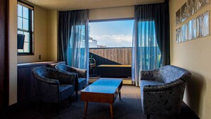 A room with two patterned armchairs, a wooden coffee table, and a view of the outdoors through large windows with curtains. - Hotel ZIZI Kyoto Gion (Kyoto)