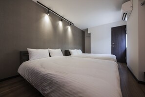 A modern hotel room with two beds, a dark door, and a ceiling-mounted air conditioner. - Shiki Homes RURI (Osaka)