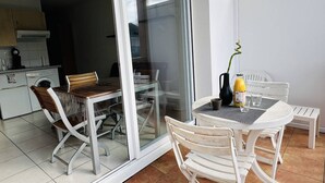 Una cocina moderna con lavadora, zona de comedor con mesa y sillas, y puerta corrediza de vidrio que da a un balcón.