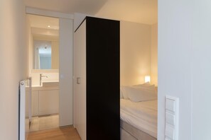 Cozy retreat with a single bed, nightstand, and access to a bathroom with sink and mirror.