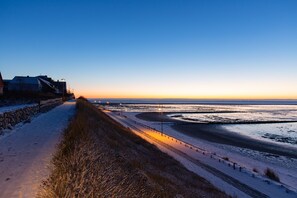 Walk along the beachside path, lined with street lamps and a stone wall, to the ocean's edge.