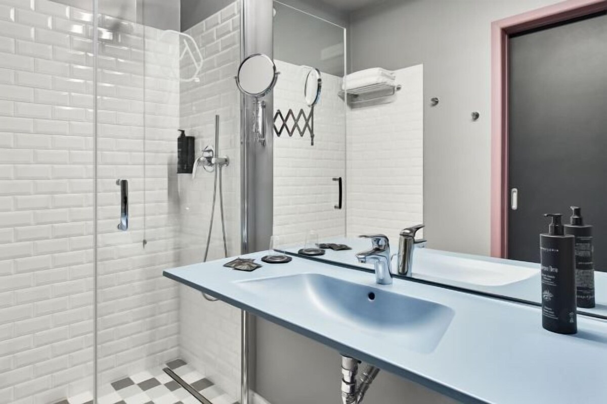 A modern bathroom with a glass shower enclosure, a large mirror, and a dual sink vanity.
