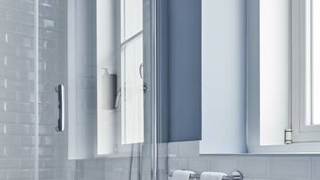 A modern bathroom with a glass shower enclosure, a white sink, and a large window providing natural light.