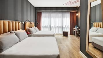 A hotel room with two beds, a desk, a chair, a mirror, and a large window with curtains.