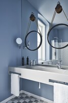 Un baño moderno con un lavabo blanco, dos espejos y un perchero para toallas.