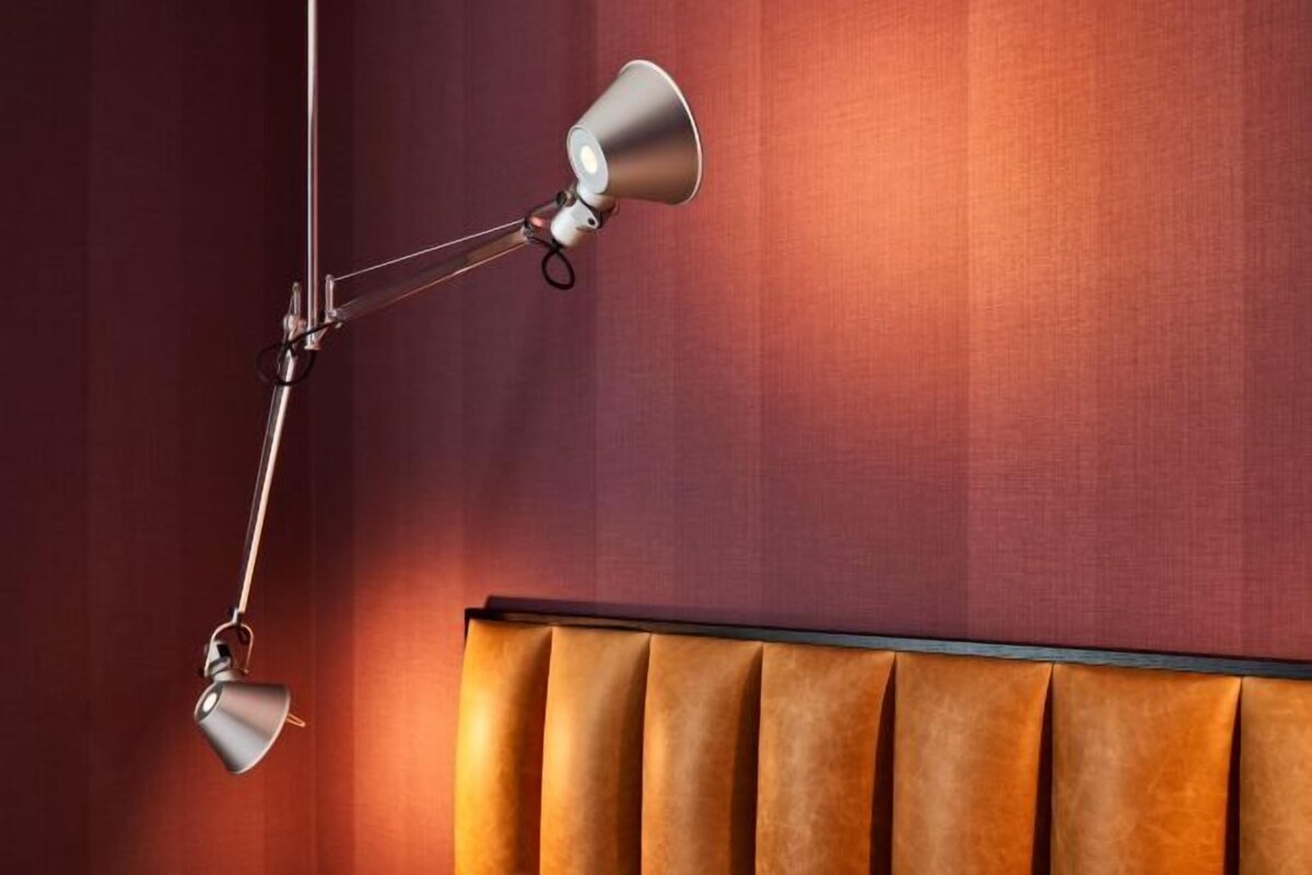 A room with a hanging floor lamp and a padded headboard.