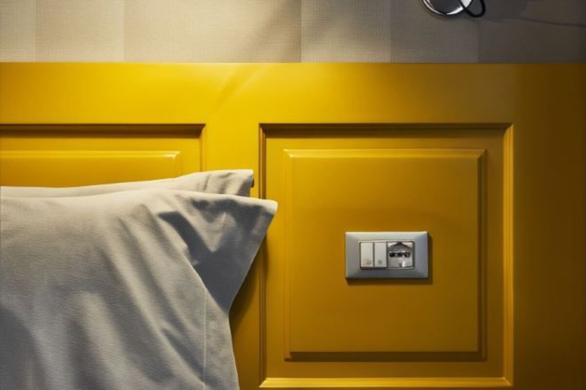 A room with a yellow door and a light switch.