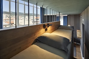 A room with a bed, a window with curtains, and a city view.