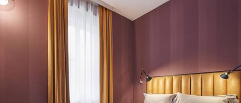 A modern hotel room with a large bed, a desk, and a chair.