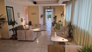 Un'ampia hall con divani color beige, un tavolino da caffè e piante in vaso.