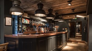 A bar area with a long counter, shelves with bottles, and hanging lights. - The Pickled Parson of Sedgefield (Stockton-on-Tees)