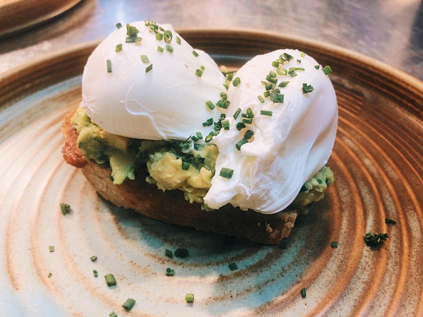 A breakfast dish with poached eggs, avocado, and chives on toast.