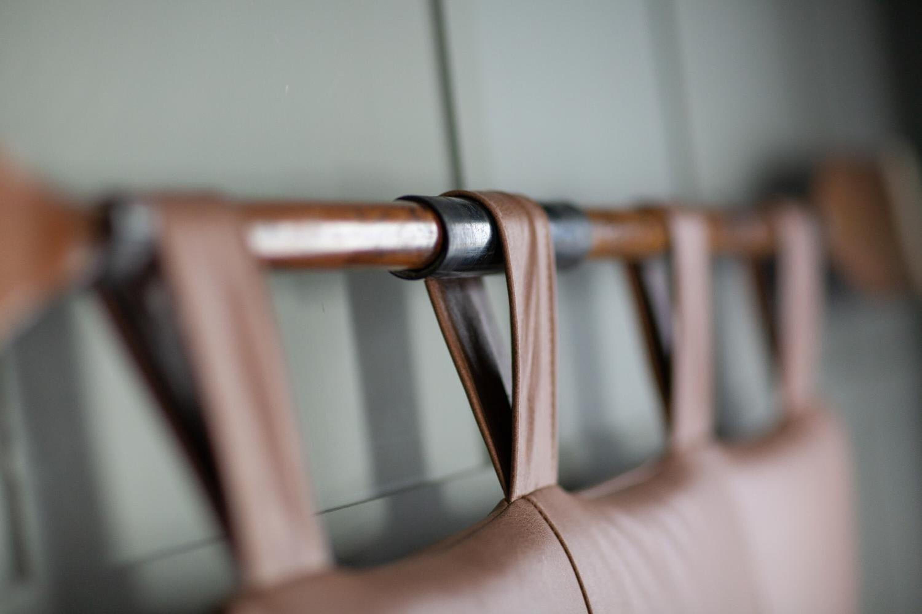 A close-up of a chair with a metal frame and leather straps.