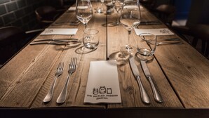 A wooden dining table set with wine glasses, cutlery, and a menu at The Pickled Parson in Sedgfield. - The Pickled Parson of Sedgefield (Stockton-on-Tees)