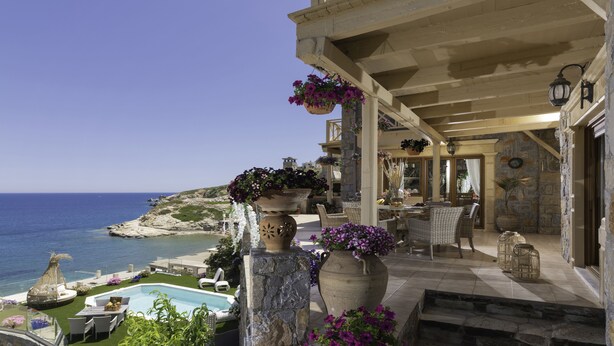 A poolside area with a view of the sea, stone pillars with planters, wicker furniture, and a stone staircase. - Felini Palace (Malevizi)