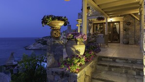 A stone staircase leading to a covered outdoor area with potted plants and wicker furniture. - Felini Palace (Malevizi)