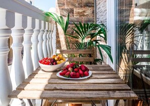 A wooden table with a bowl of fruit and a plate of strawberries on a balcony. - Hostal Poseidón (San Bartolomé de Tirajana)