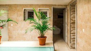 A modern bathroom with a glass-enclosed shower, a potted plant, and a tiled floor. - Hostal Poseidón (San Bartolomé de Tirajana)