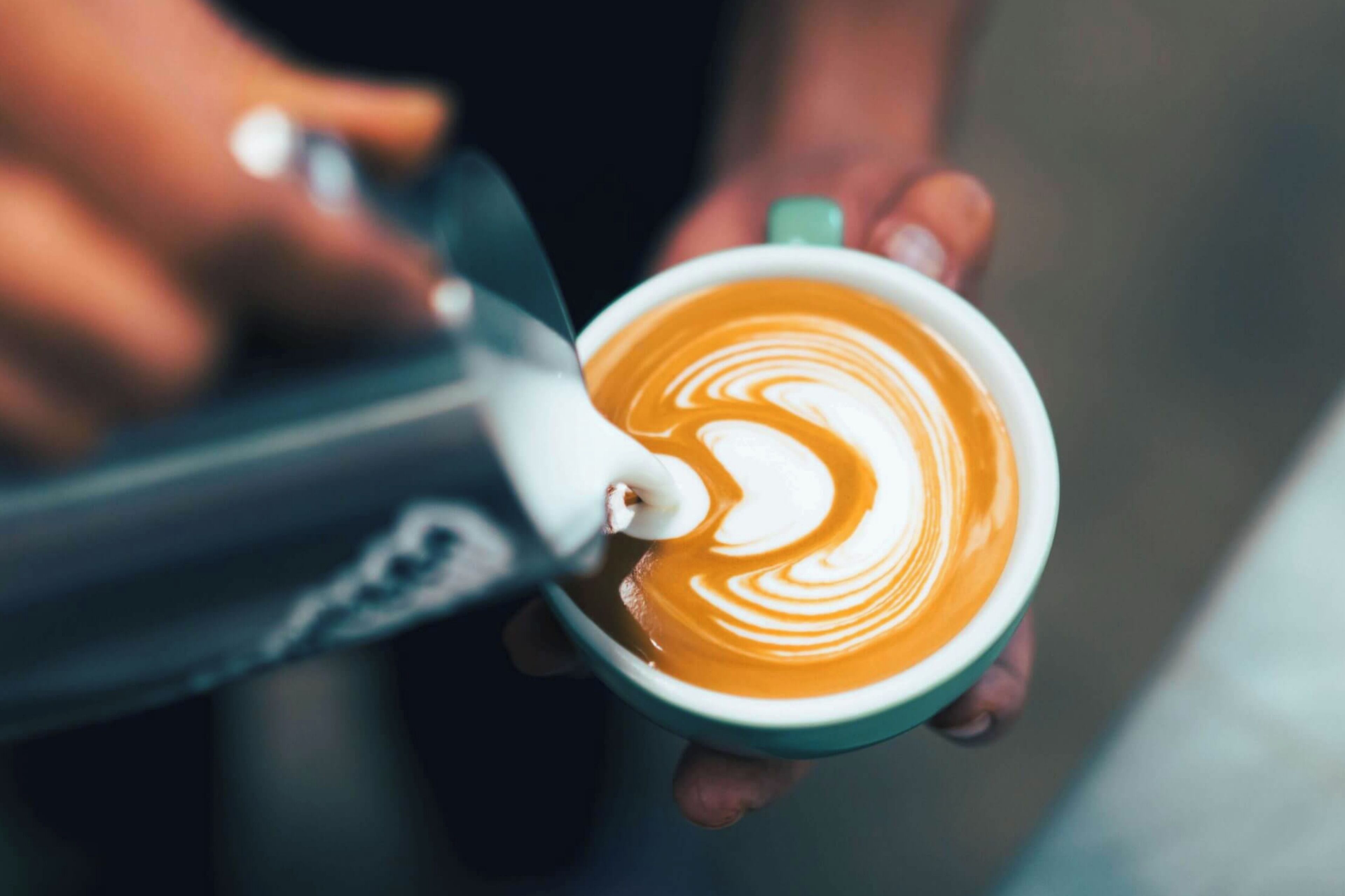 A close-up of a person holding a cup of coffee with latte art.
