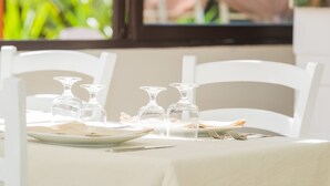 Ein Tisch gedeckt mit weißen Stühlen, klarem Glas und Tellern.