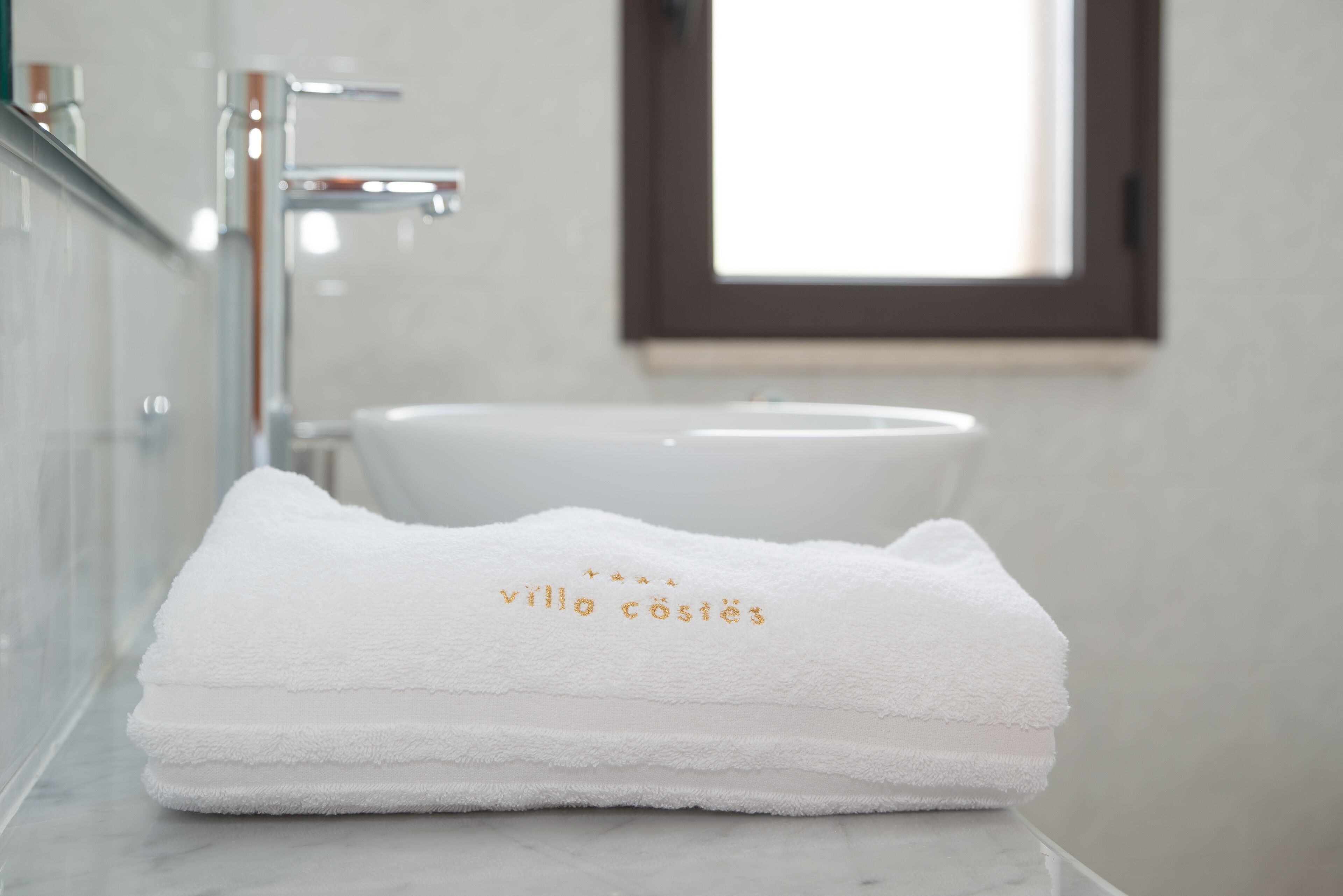 A neatly folded white towel with embroidered text on a bathroom counter.