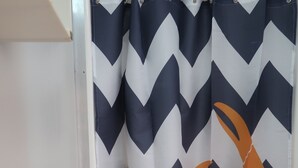 A bathroom with a white sink, a towel rack, and a shower curtain with a crab pattern. - Mud Crab Motel (Derby)