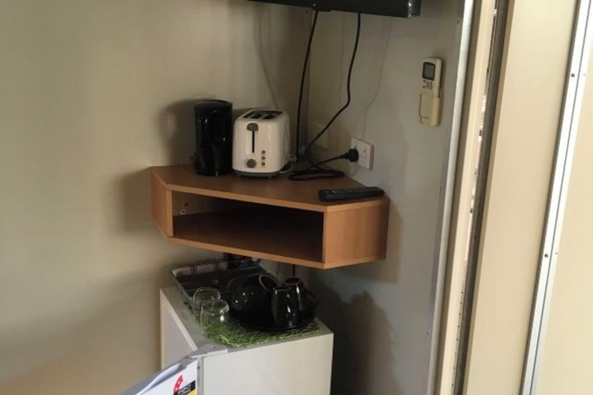 A kitchen area with a toaster, a kettle, and a coffee maker on a small table.