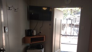 A compact kitchen with a refrigerator, a coffee maker, and a microwave on a shelf. A flat-screen TV is mounted on the wall. - Mud Crab Motel (Derby)