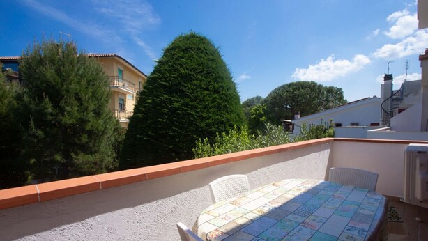 A rooftop terrace with a table and chairs, surrounded by buildings and trees. - M200 - Marcelli, new two-room apartment 200mt from the sea (Marcelli)