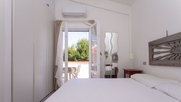 A bedroom with a bed, a desk, a chair, and an open door leading to an outdoor area. - M200 - Marcelli, new two-room apartment 200mt from the sea (Marcelli)
