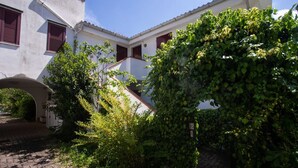 A courtyard with a white building, red shutters, and a stone pathway. - M200 - Marcelli, new two-room apartment 200mt from the sea (Marcelli)