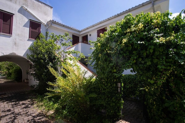 A courtyard with a white building, red shutters, and a stone pathway.