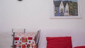 A room with a bed, a red pillow, a quilted tablecloth, a framed painting, and a clock on the wall. - M200 - Marcelli, new two-room apartment 200mt from the sea (Marcelli)