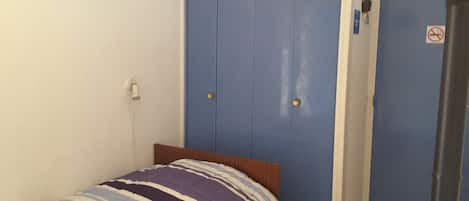Ein Schlafzimmer mit einem Bett, einer blauen Tür und einer weißen Wand.