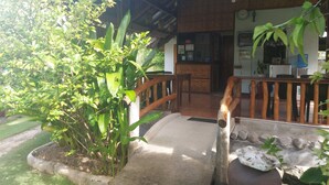 A wooden porch with a concrete ramp leading to a building with a tiled roof. - Gardenview Homestay Siargao (General Luna)