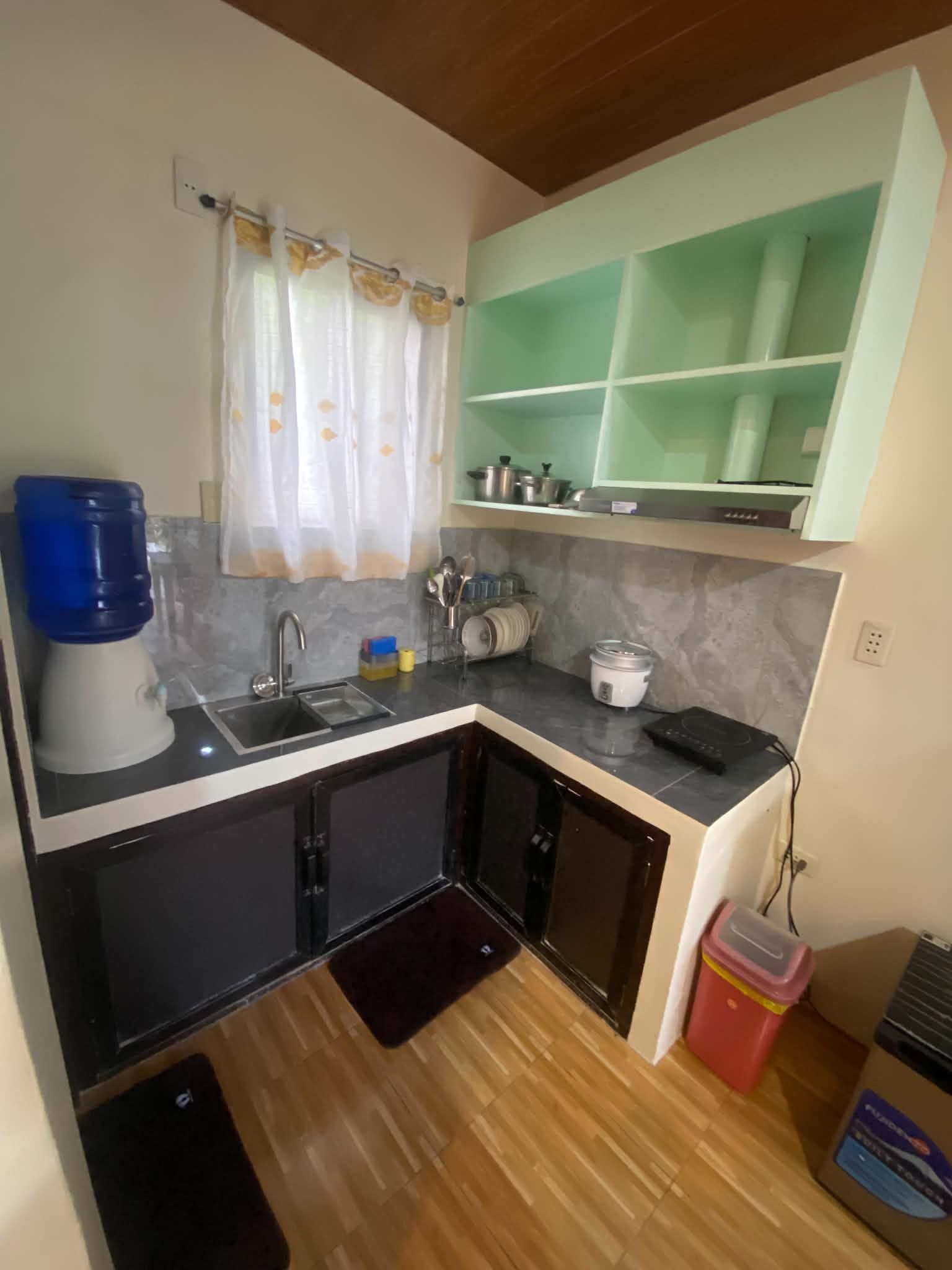 Cocina compacta con lavamanos, dispensador de agua y microondas.