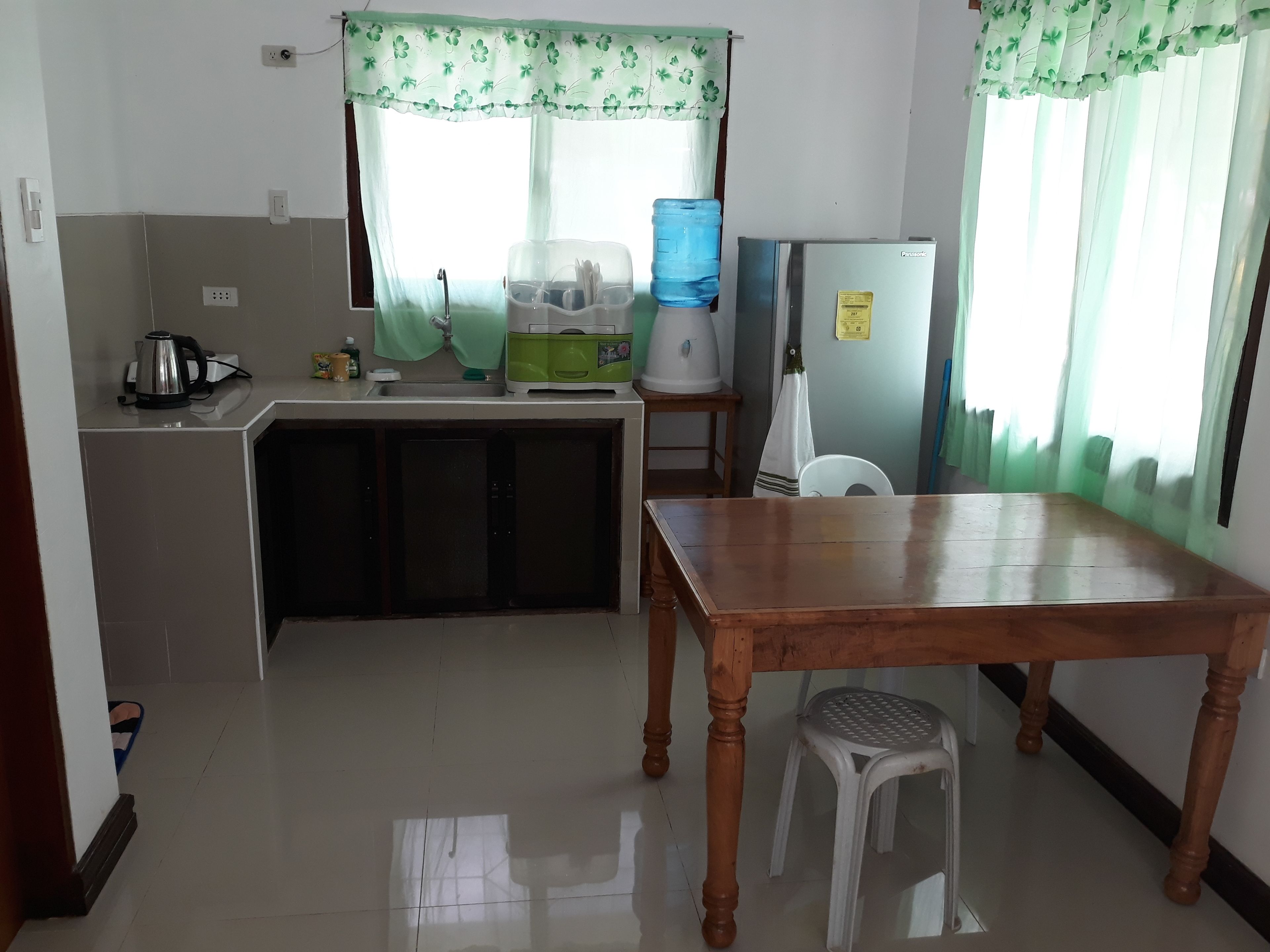 Cocina compacta con lavamanos, hervidor, dispensador de agua y refrigerador.