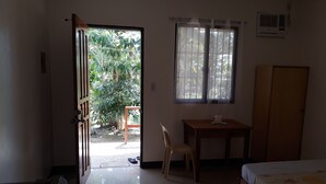 A room with a bed, a desk, a chair, and a window with curtains. - Gardenview Homestay Siargao (General Luna)
