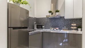 Una cocina moderna con microondas integrado, armarios de acero inoxidable y un refrigerador con puerta de vidrio.