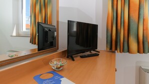 Une chambre d’hôtel équipée d’une télévision, d’une télécommande, d’un bol de collations et d’une fenêtre avec des rideaux.