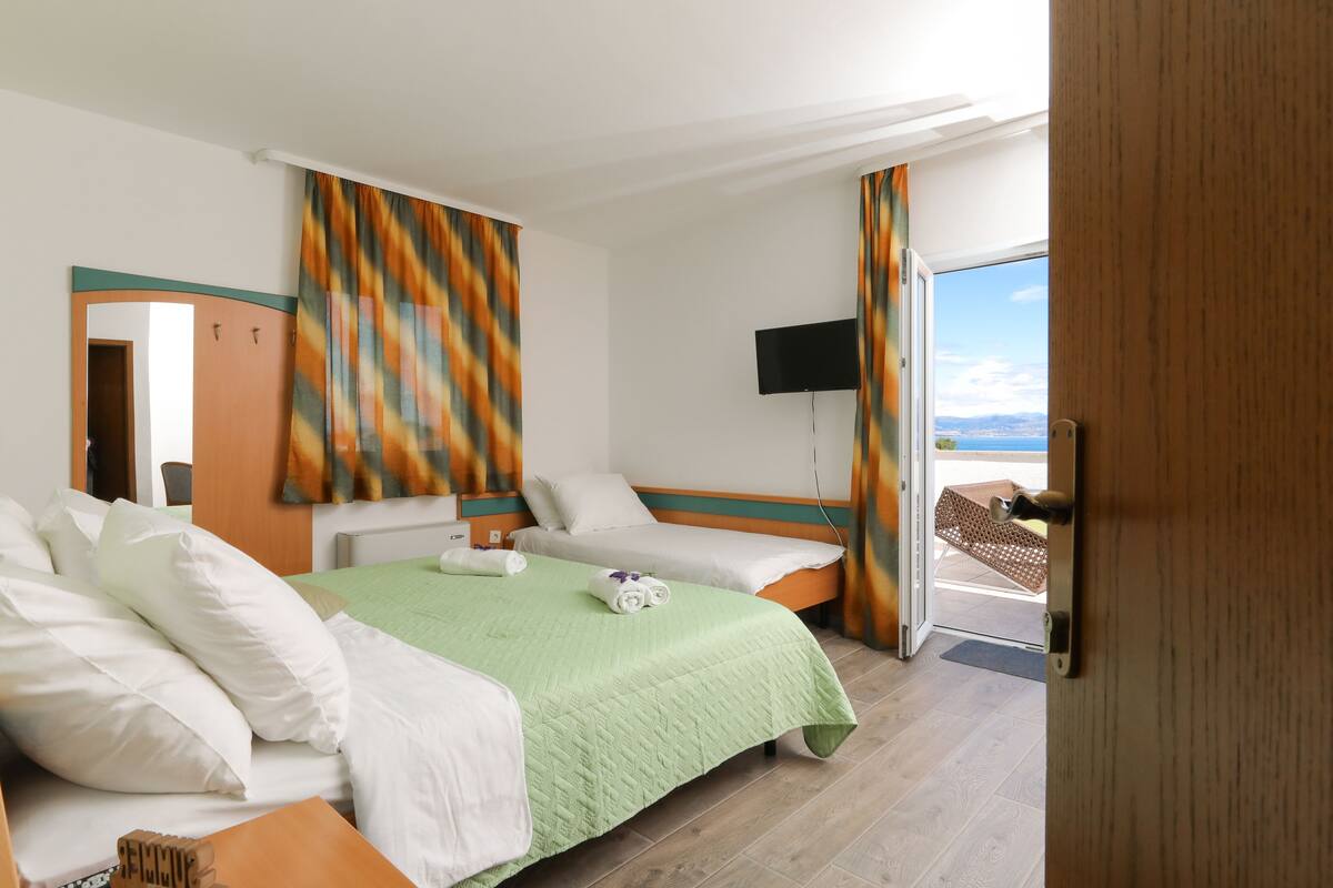 A hotel room with a bed, a TV, and a view of the outdoors.