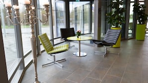 A modern lobby with a candelabra, two chairs, a table, and a potted plant. - ICV SleepWell (Vra)