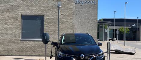 A black car parked in front of a building with a sign that reads "IDRATSCENTER dsyssel".