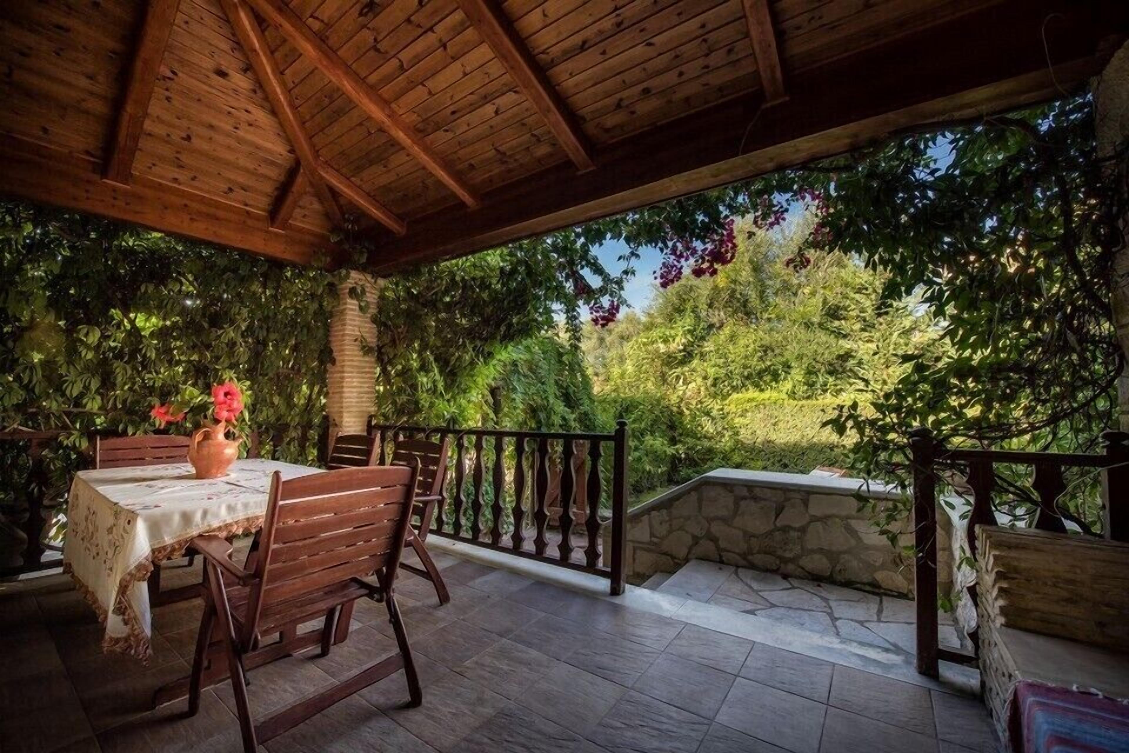 An outdoor patio with wooden furniture and a stone wall.