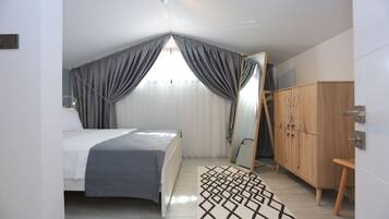 A bedroom with a bed, a wardrobe, a mirror, and a geometric rug.