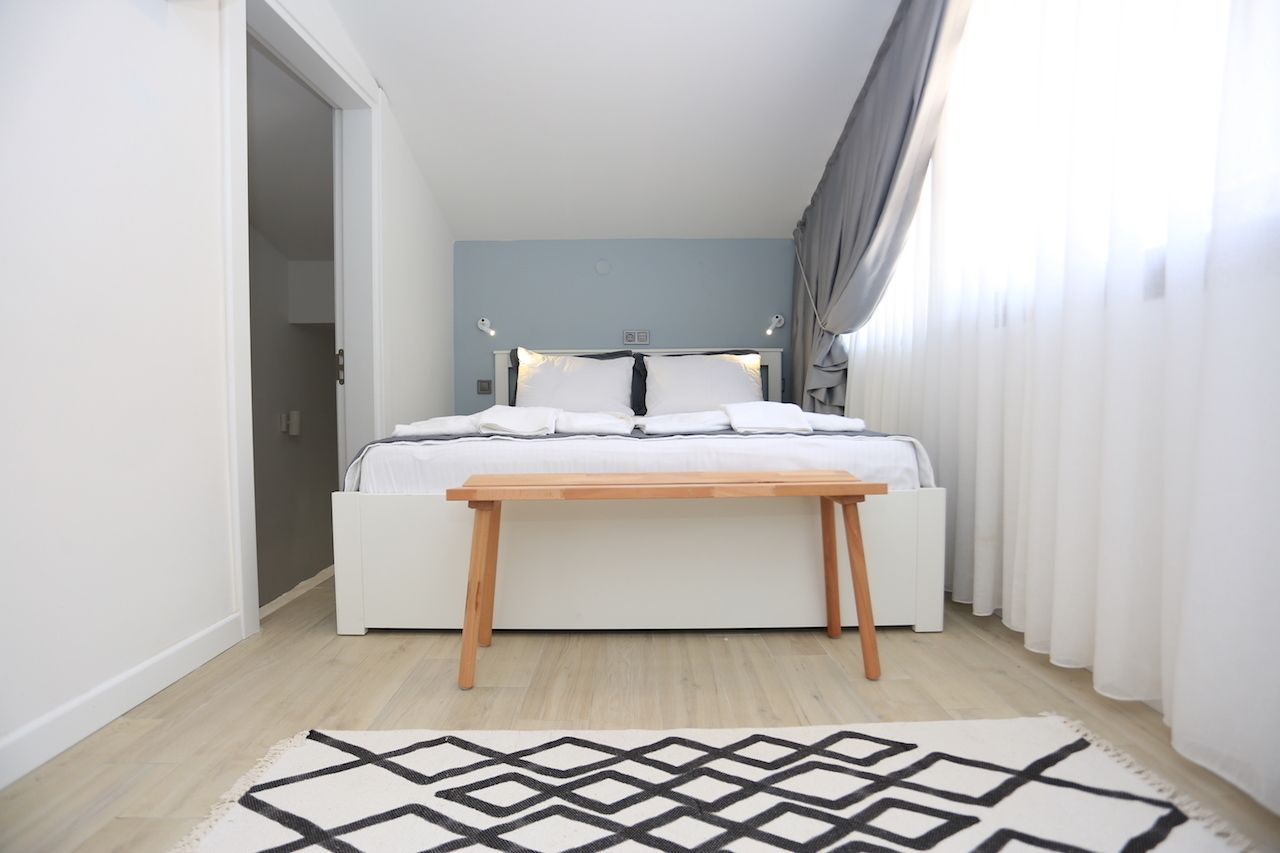 Ein Schlafzimmer mit einem Bett, Nachttischen, einer Holzbank und einem gemusterten Teppich.